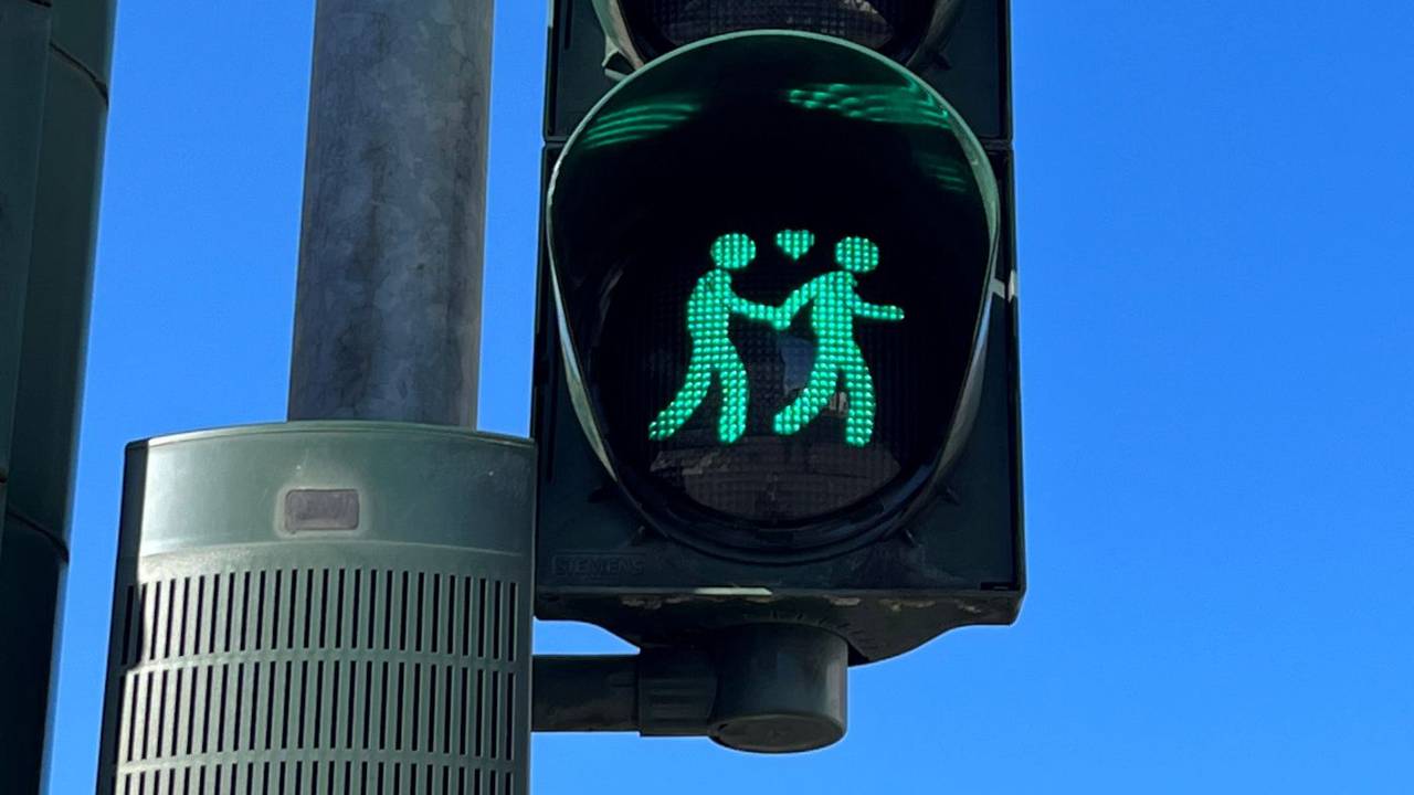 Das Foto zeigt eine Ampel mit einem gleichgeschlechtlichen Paar, zwischen ihnen befindet sich ein Herz. Die beiden Figuren leuchten grün.