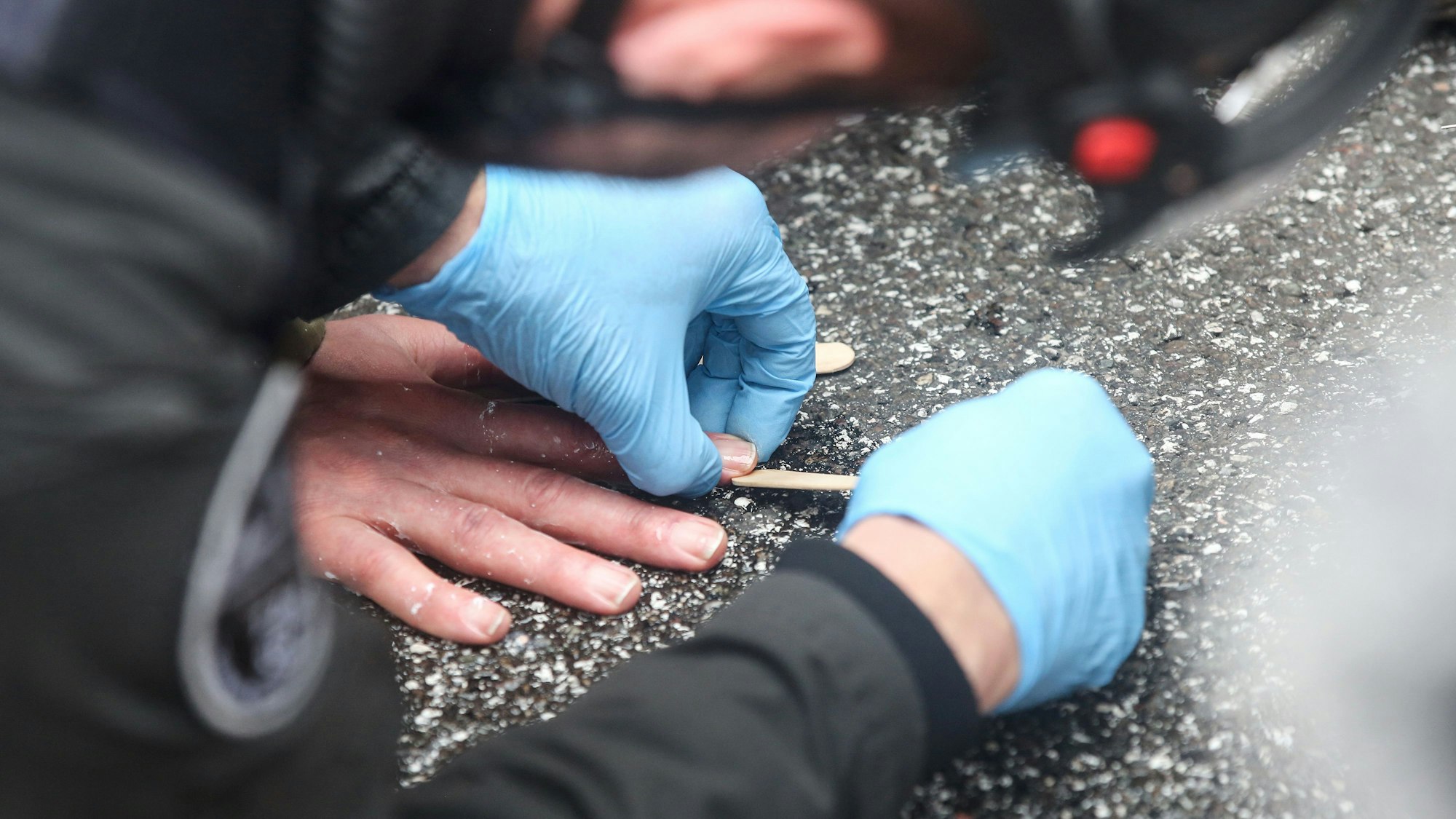 Das Symbolfoto aus dem Jahr 2023 zeigt einen Polizisten, der die auf der Straße festgeklebte Hand eines Aktivisten der „Letzten Generation“ zu lösen versucht.