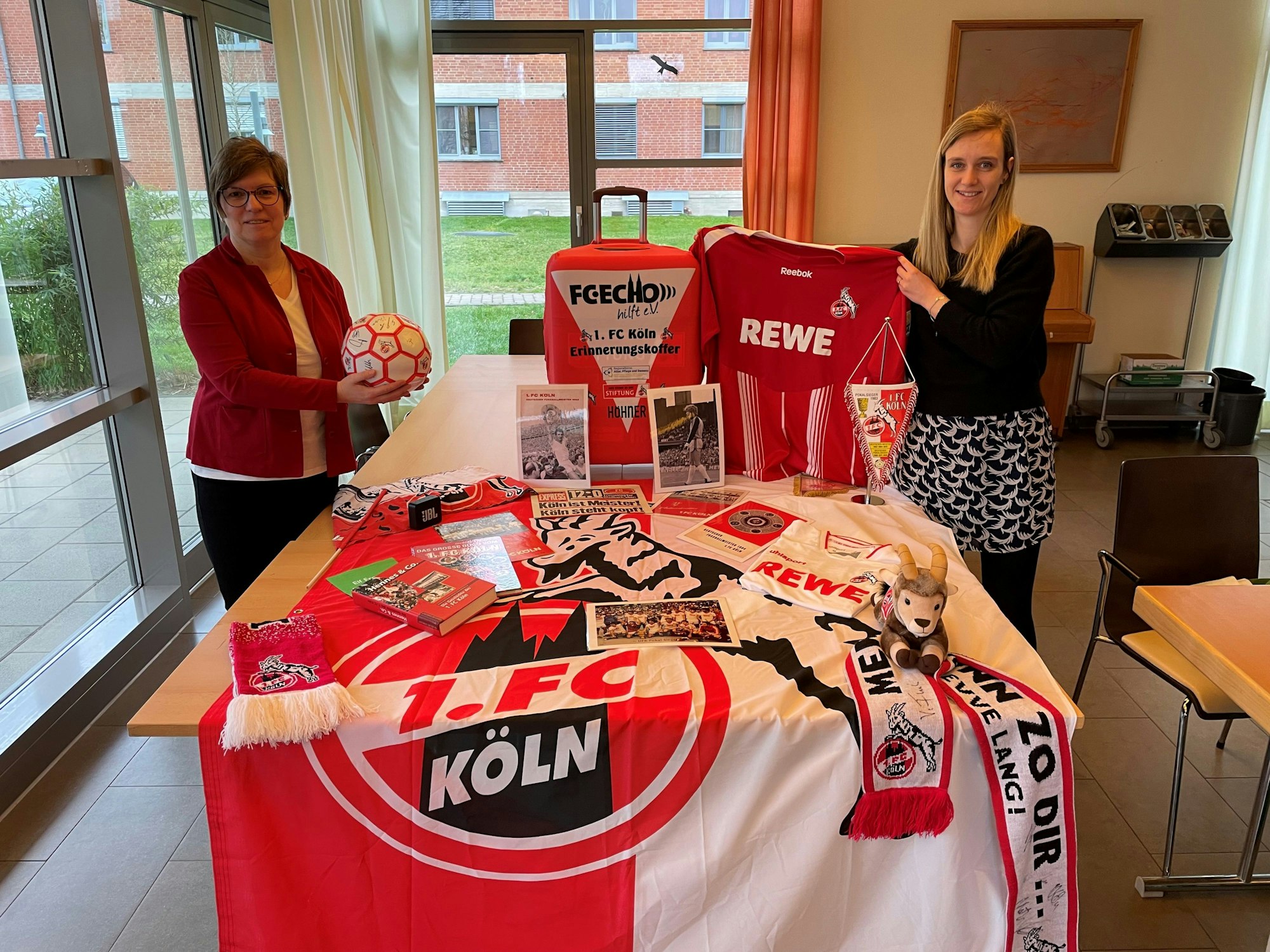 Martina Romeike und Nadine Diederich-Cujai zeigen die Fan-Utensilien aus dem Erinnerungskoffer.