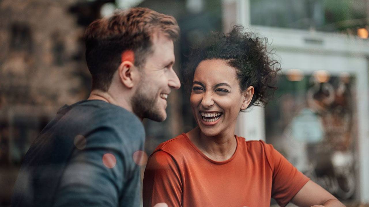 Mann und Frau sitzen im Cafe und lachen gemeinsam