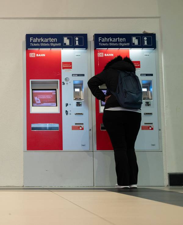 Eine Frau steht im Hauptbahnhof an einem Fahrkartenautomaten.