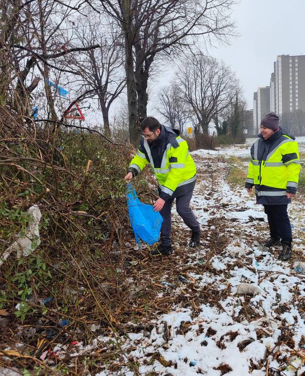 Hier pflücken drei städtische Mitarbeiter Plastikmüll aus den Sträuchern in Köln-Meschenich.