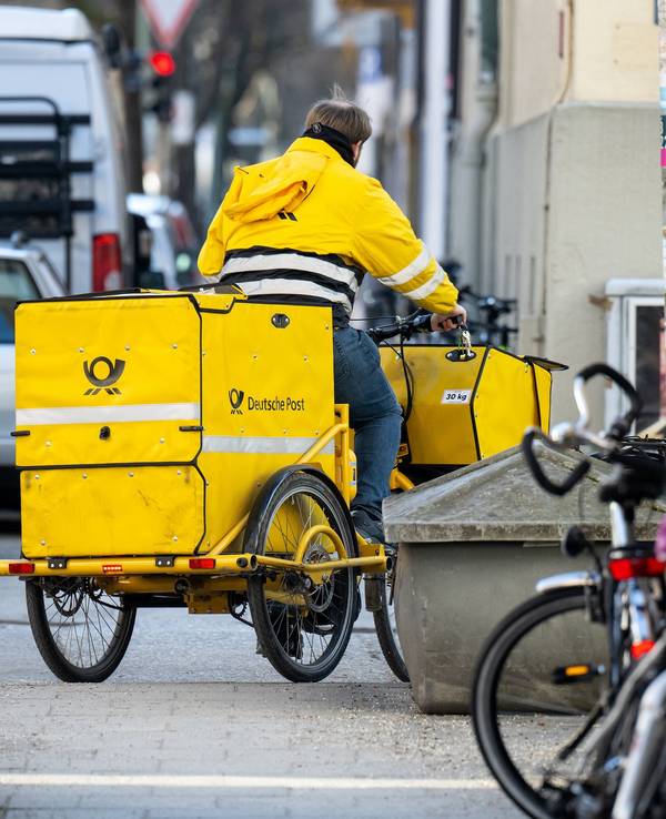 Das undatierte Foto zeigt einen Mitarbeiter der Deutschen Post. Er trägt Briefe mit einem gelben Lastenfahrrad aus.