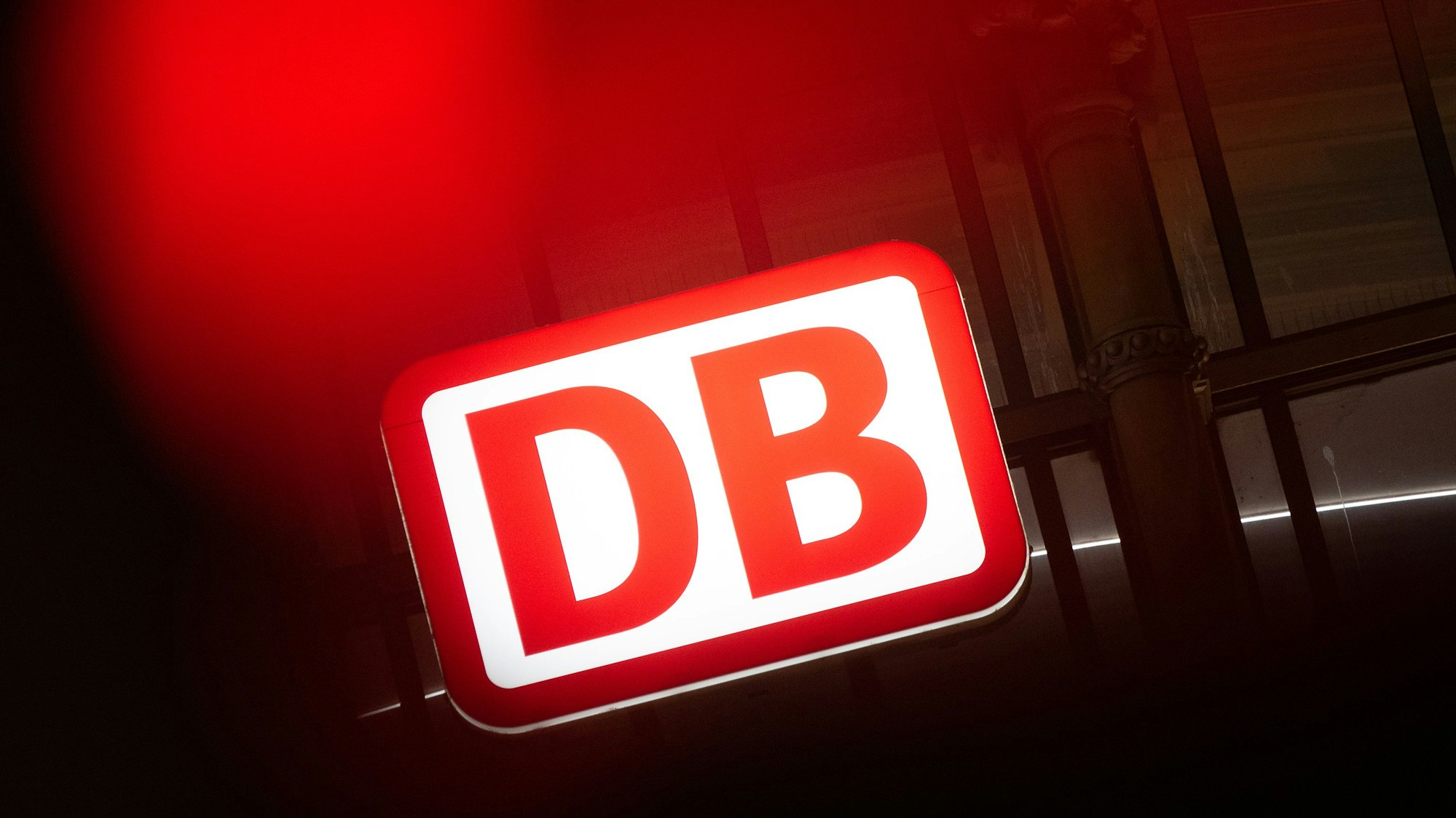 Das Logo der Deutschen Bahn leuchtet am Hauptbahnhof hinter einer Ampel.