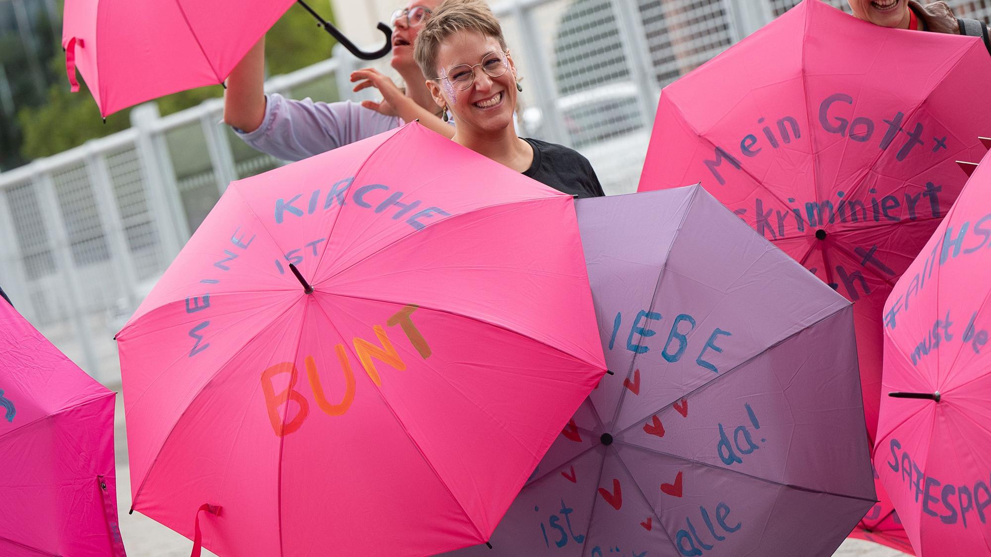Mitglieder unterschiedlicher katholischer Jugendverbände halten zu Beginn der vierten Synodalversammlung der katholischen Kirche in Deutschland im Congress Center Messe Frankfurt vor dem Eingang Schirme mit Botschaften wie „Meine Kirche ist Bunt“ zur Unterstützung der Vielfalt in der katholischen Kirche hoch.