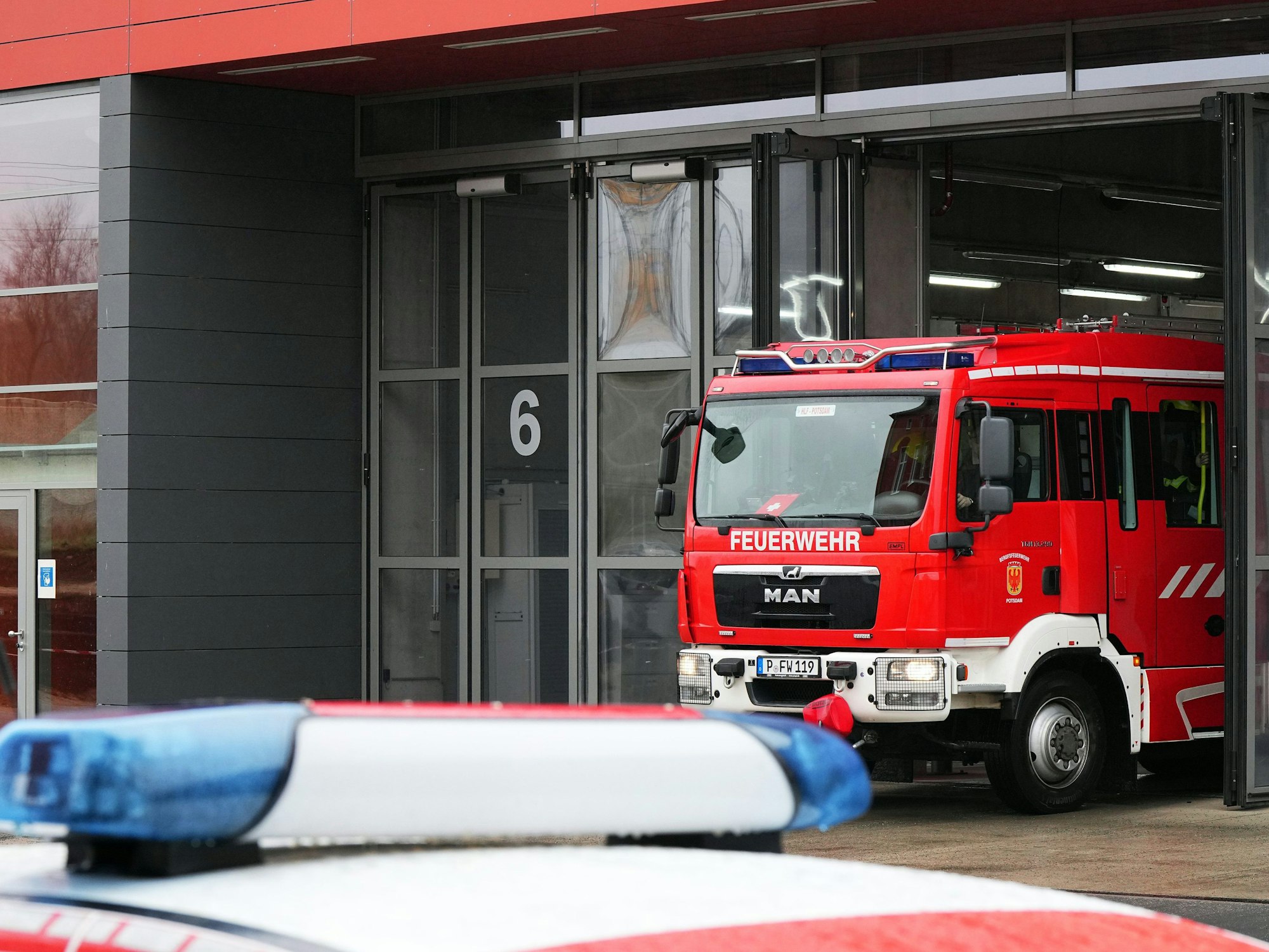 Auf dem Bild sieht man ein Feuerwehrfahrzeug aus Potsdam. Es fährt aus dem Eingang einer Feuerwehrzentrale.