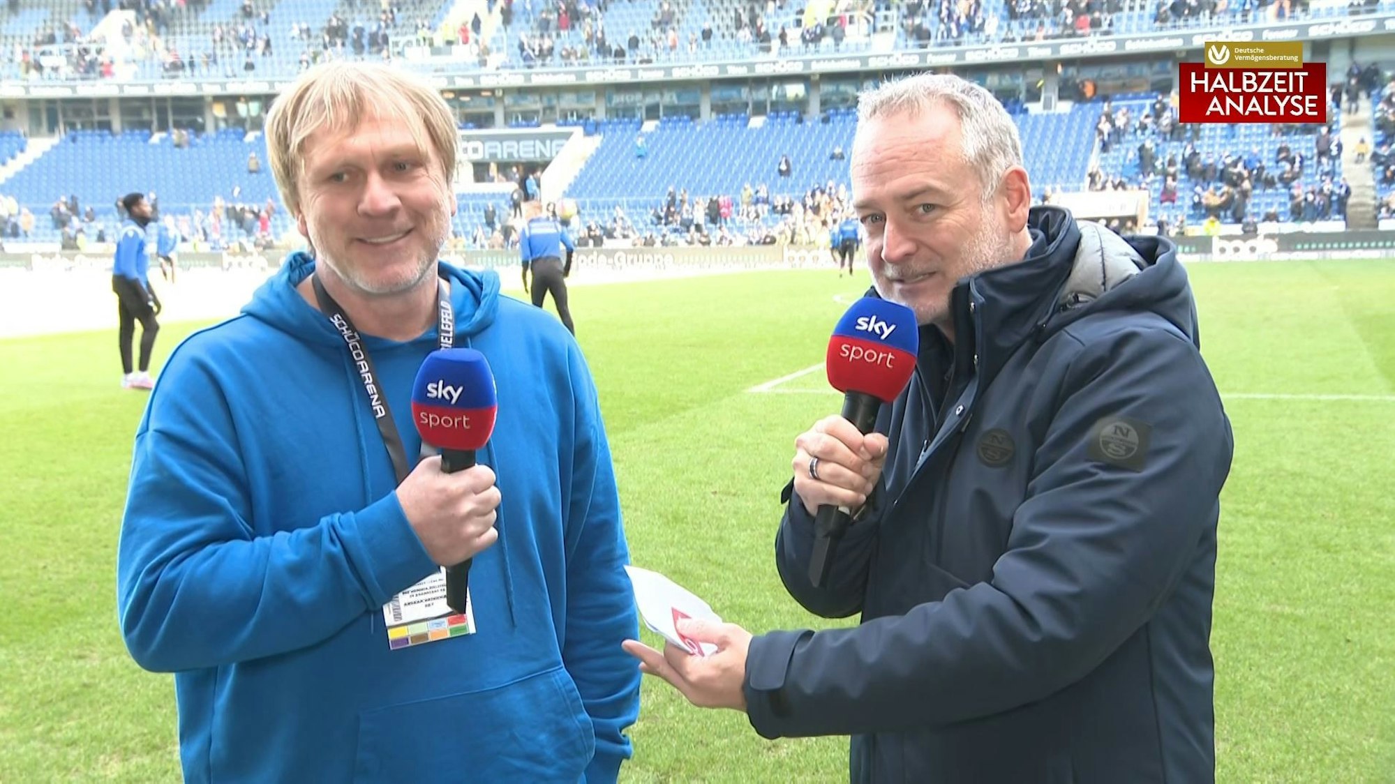 Stefan Hempel (r.) und Ansgar Brinkmann blicken bei der Sky-Übertragung zum Spiel zwischen Arminia Bielefeld und Darmstadt 98 in die Kamera.