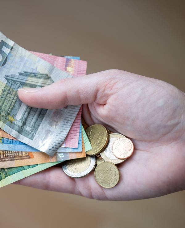 Eine Frau hält Geldscheine und Münzen in der Hand.
