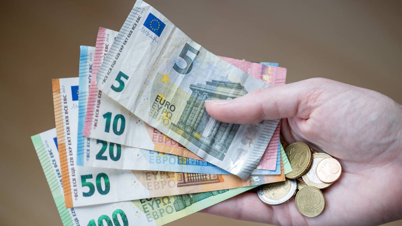 Eine Frau hält Geldscheine und Münzen in der Hand.