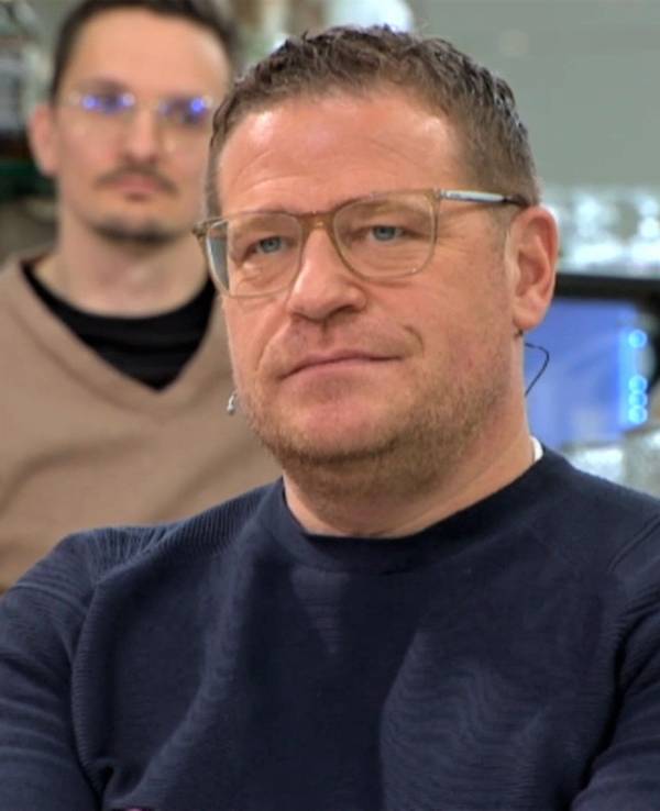 Max Eberl sitzt im Doppelpass auf Sport1 und blickt in die Kamera.