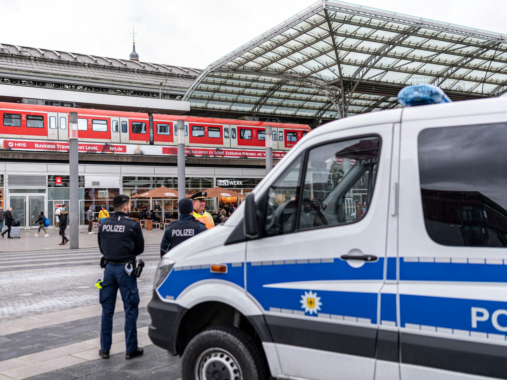 Ein Polizei-Auto und mehrere Beamte stehen vor dem Kölner Hauptbahnhof.