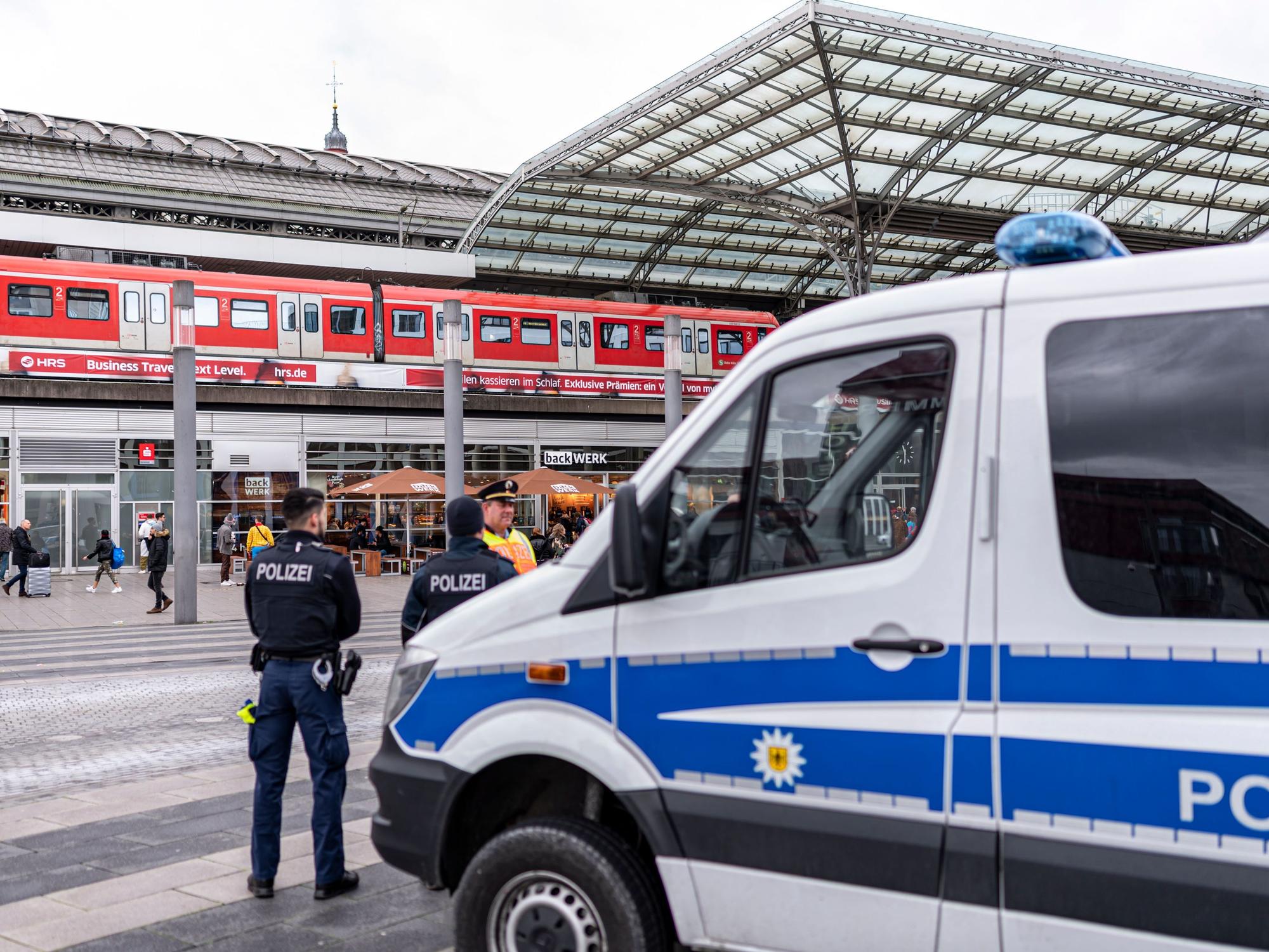 Ein Polizei-Auto und mehrere Beamte stehen vor dem Kölner Hauptbahnhof.