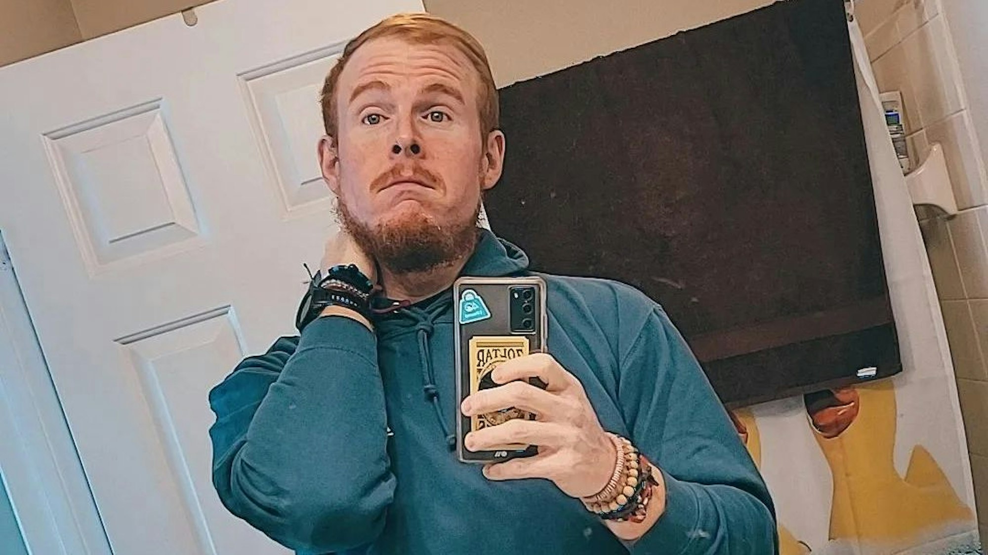 Casey King posiert vor einem Spiegel für ein Selfie. Er trägt einen blauen Kapuzenpullover.