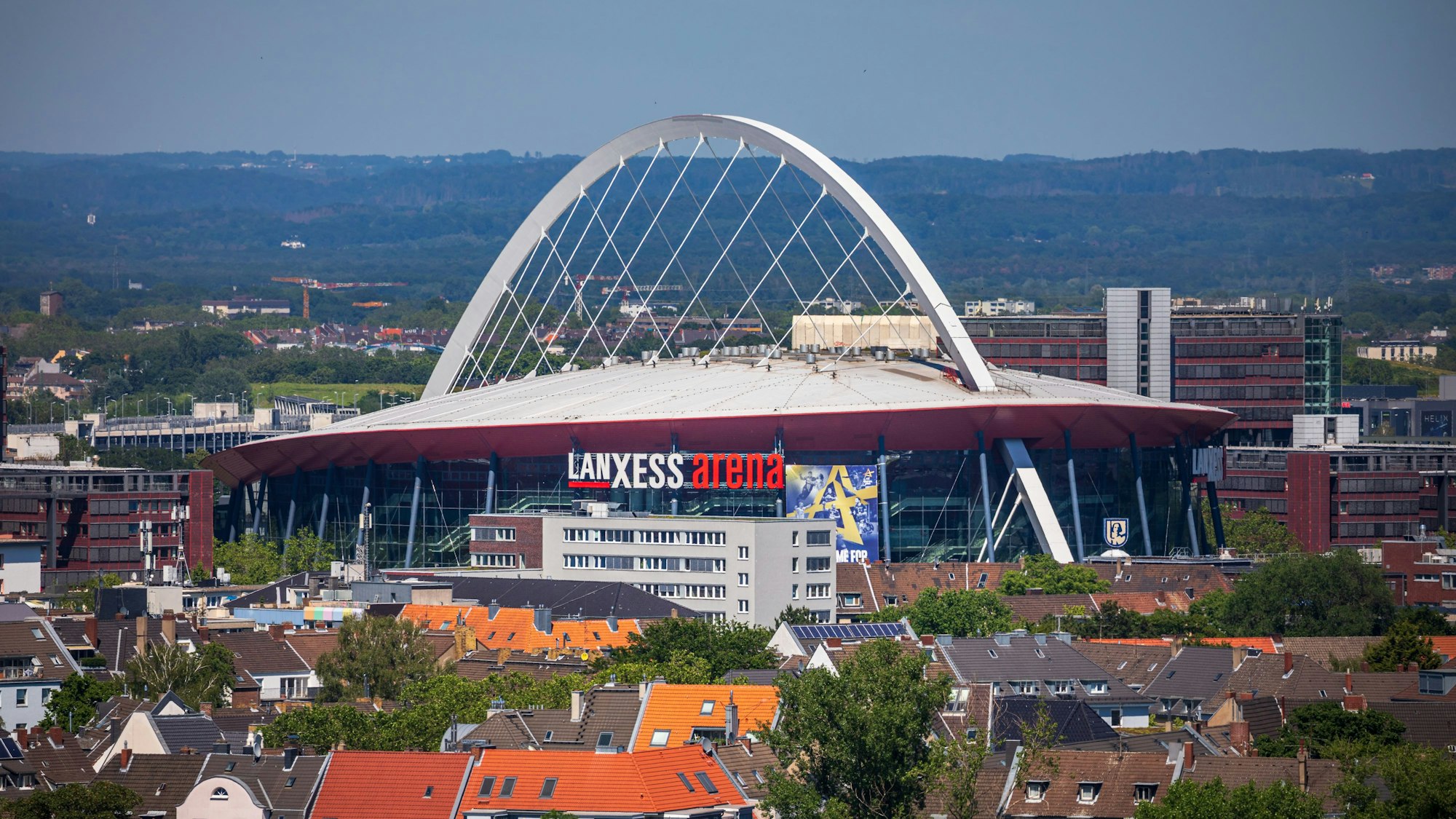 Die Lanxess Arena in Köln inmitten von Häusern.