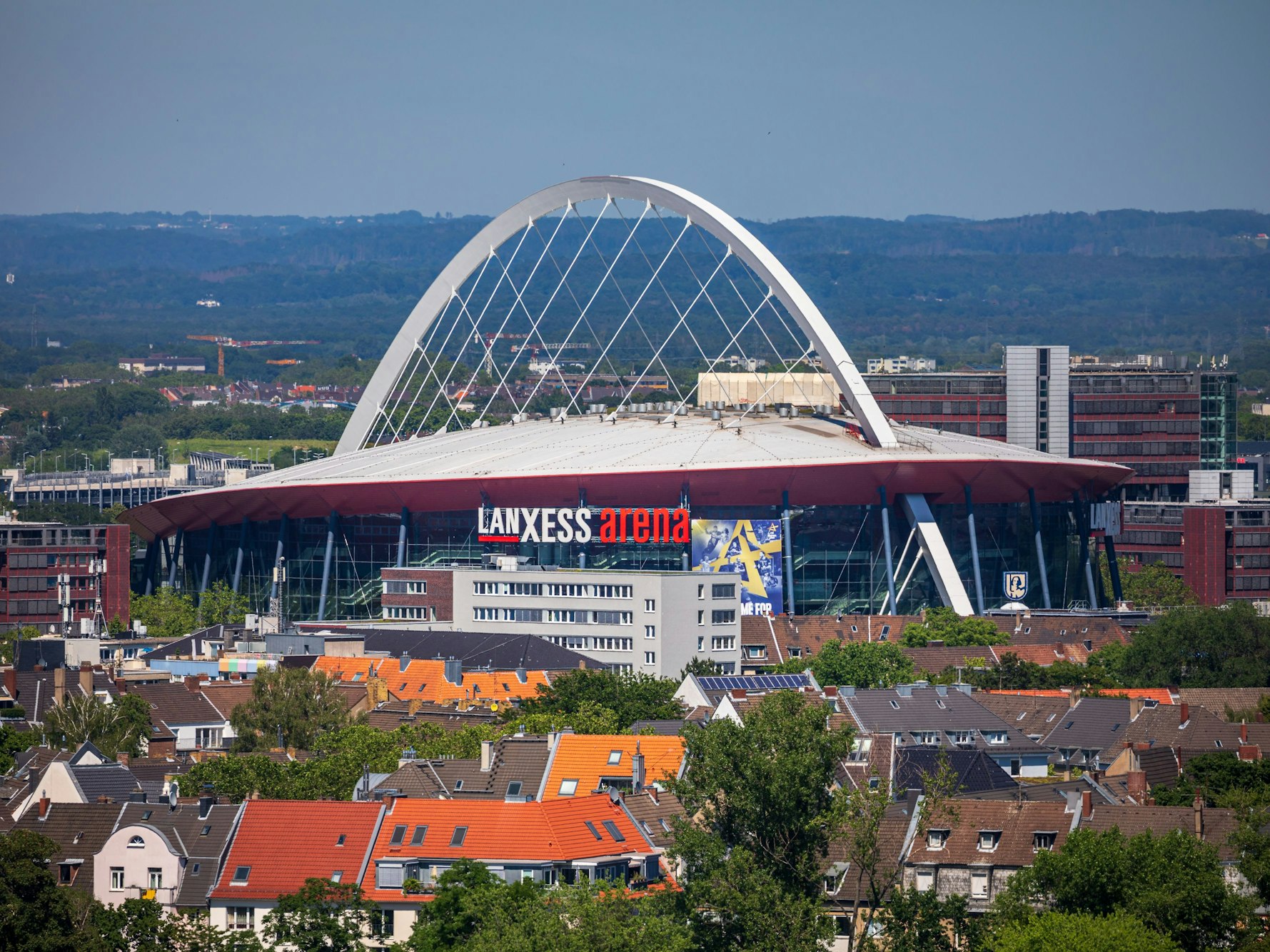 Die Lanxess-Arena, früher als Kölnarena bezeichnet, ist inmitten des Kölner Stadtteils Deutz zu sehen, während der Blick bis weit in das Umland reicht.