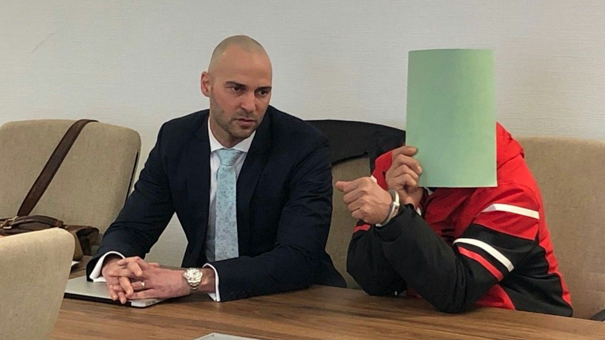 Angeklagter und Anwalt sitzen auf der Anklagebank im Kölner Gerichtsgebäude.