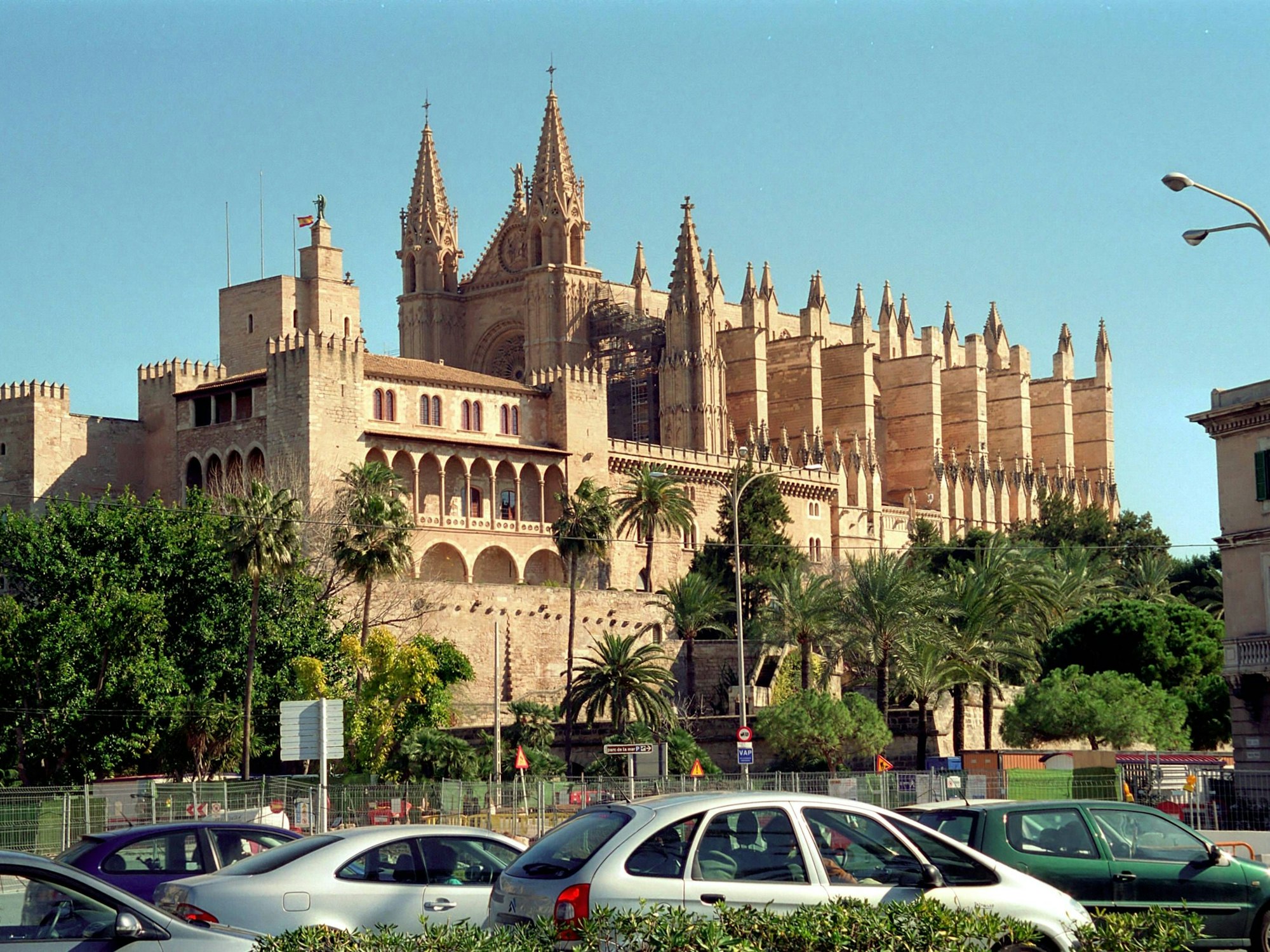 Autos stehen in Palma de Mallorca auf der Straße. Im Hintergrund: die Kathedrale La Seu.