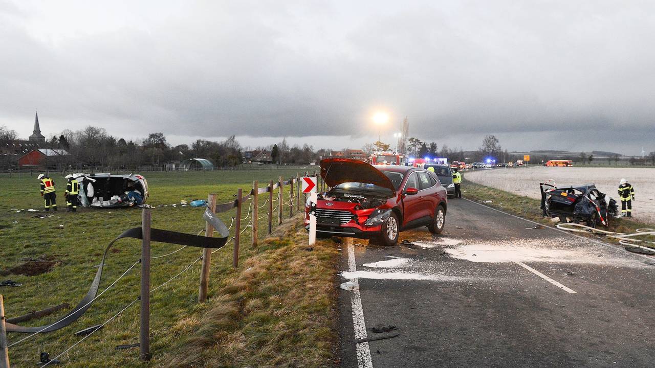 Ein zerstörtes Auto (l) liegt auf einer Wiese.