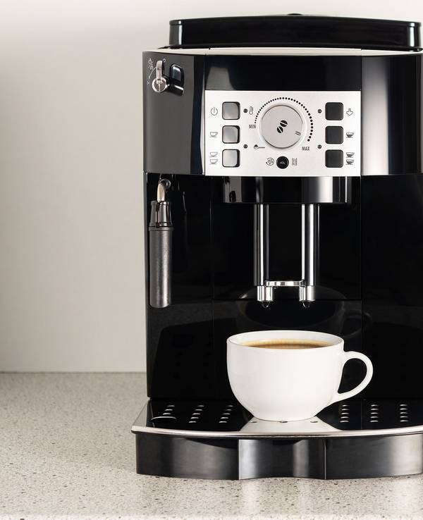 Modern espresso coffee machine with a cup in interior of kitchen closeup.
