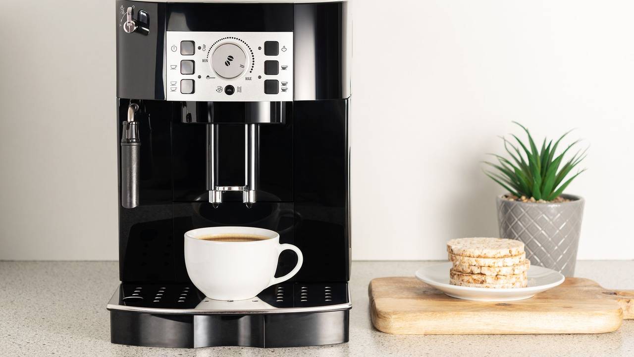 Modern espresso coffee machine with a cup in interior of kitchen closeup.