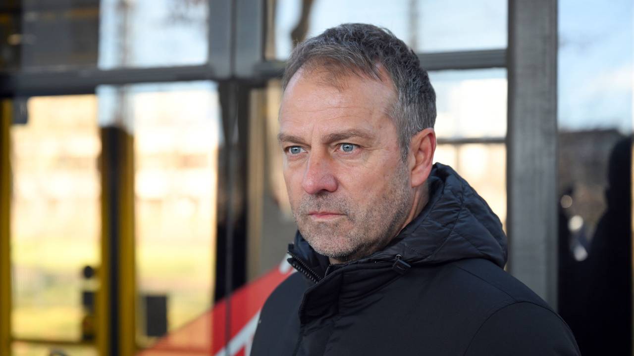 Fußball-Bundestrainer Hansi Flick steht vor einer Straßenbahn.