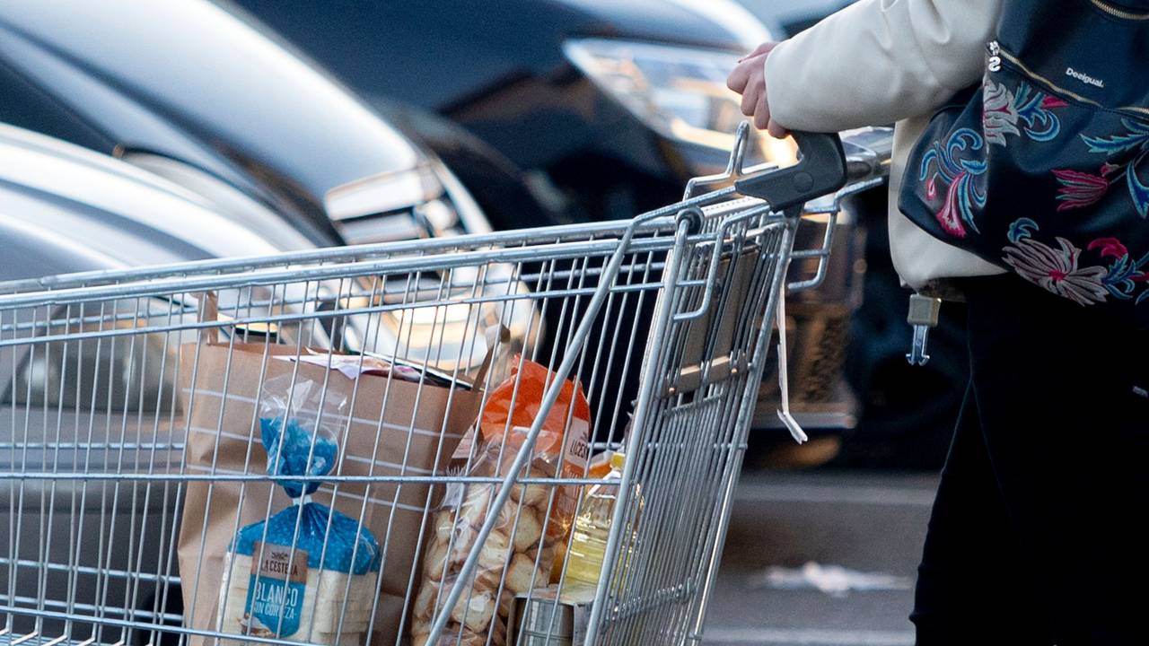Eine Frau verlässt einen Supermarkt mit einem Einkaufswagen.