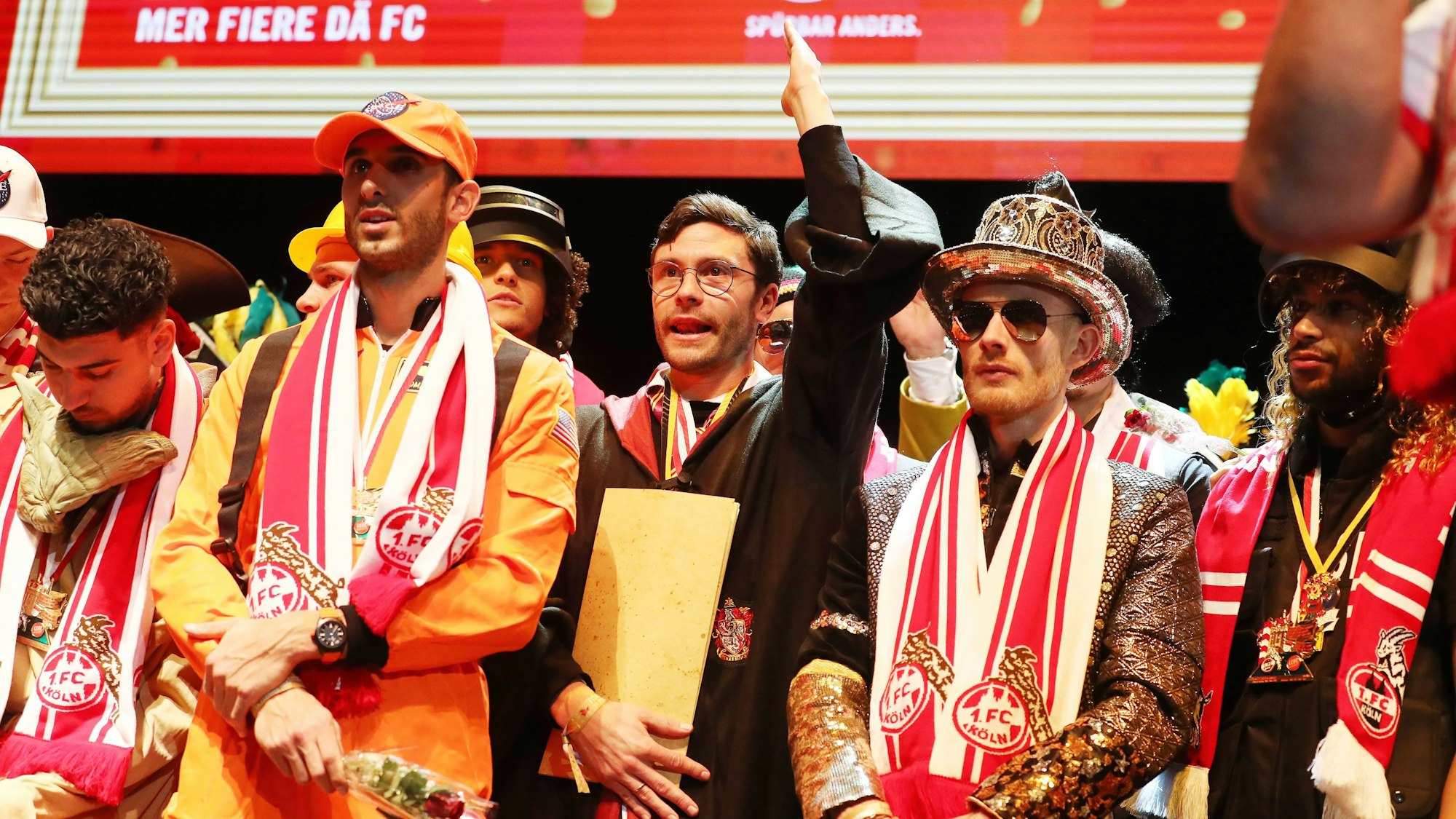 Die Profis des 1. FC Köln stehen bei der Klub-Sitzung verkleidet auf der Bühne.