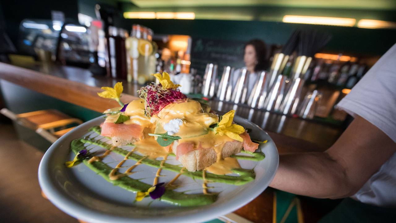 Ein Mitarbeiter des Frühstückslokals „The Gardener's Nosh“ in Stuttgart trägt im Juni 2018 während eines Fototermins einen Teller mit dem Frühstücksgericht „Benedict-Eier“, das aus pochierten Eiern, Räucherlachs, frischem Spinat und Brioche mit Beilagen besteht.