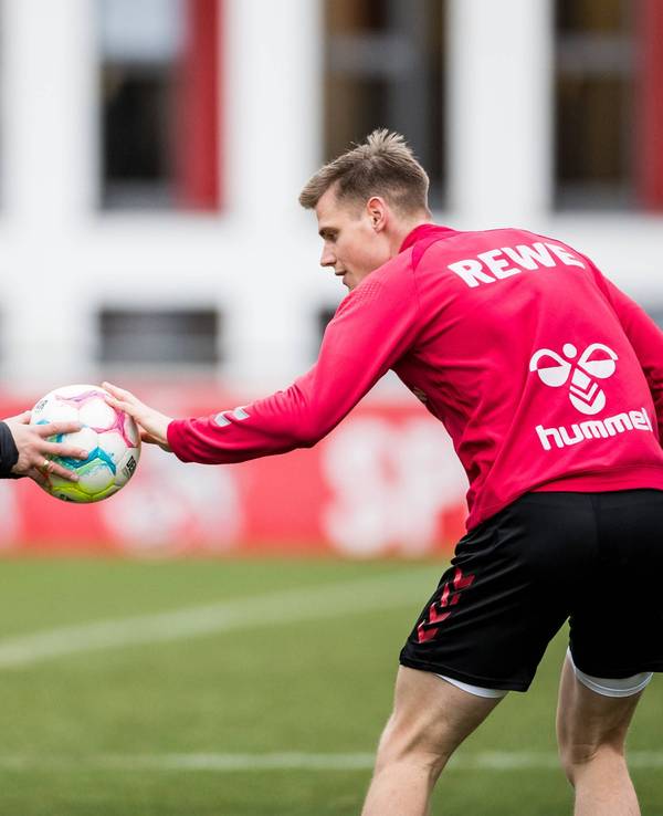 Steffen Tigges hält Steffen Baumgart im Training des 1. FC Köln einen Ball hin.