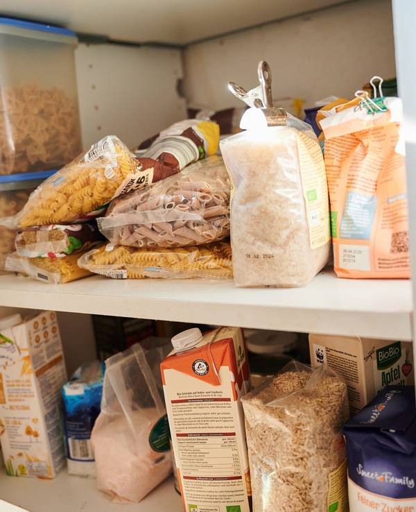 In einem Küchenschrank liegen Vorräte. Nudeln, Zucker, Mehl, Milch und Salz unterschiedlicher Hersteller sind zu sehen.