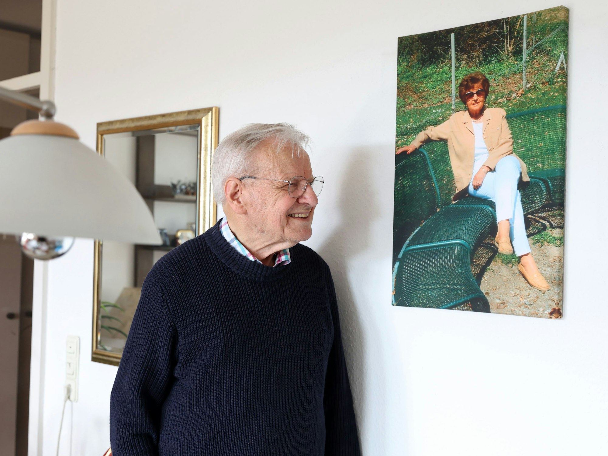 Ein Mann steht neben einem Bild, das an einer Wand hängt.