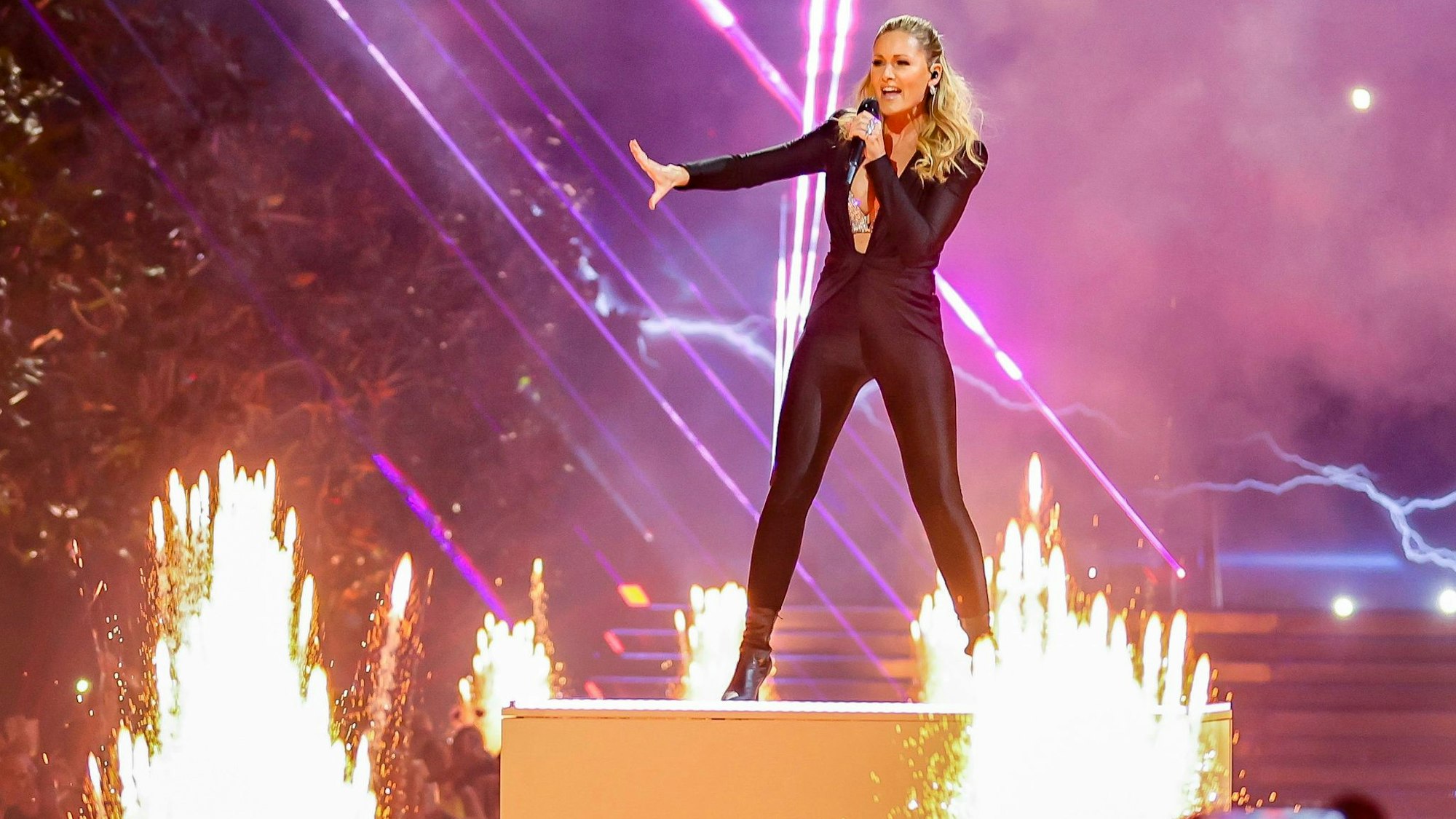 Helene Fischer singt auf der Bühne bei einem Konzert, im Hintergrund Feuerwerk.