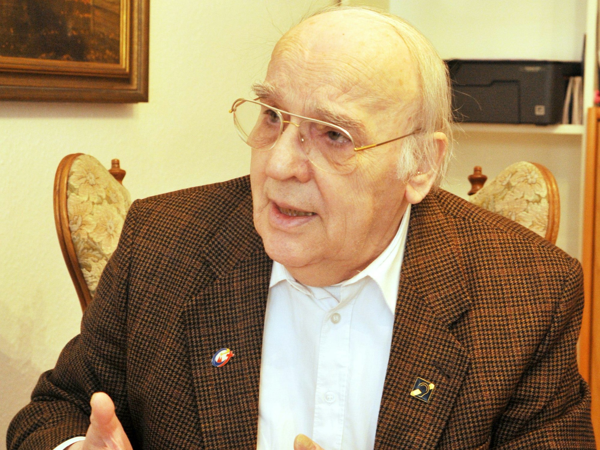 Winand Franz Jaeger sitzt in einem Stuhl und gestikuliert mit seinen Händen.