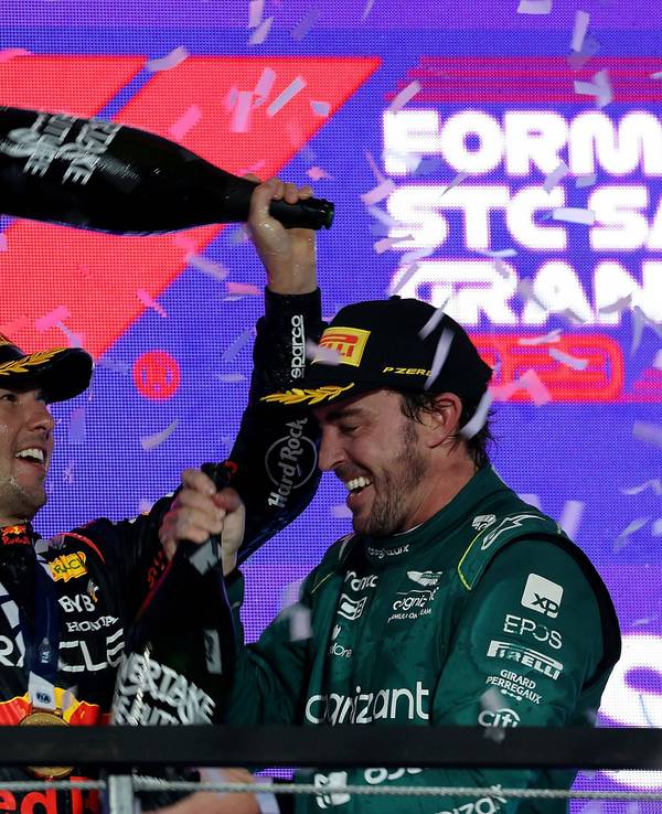 Sergio Perez schüttet Fernando Alonso Champagner über den Kopf, Max Verstappen schaut zu.