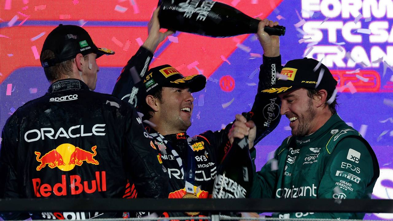Sergio Perez schüttet Fernando Alonso Champagner über den Kopf, Max Verstappen schaut zu.