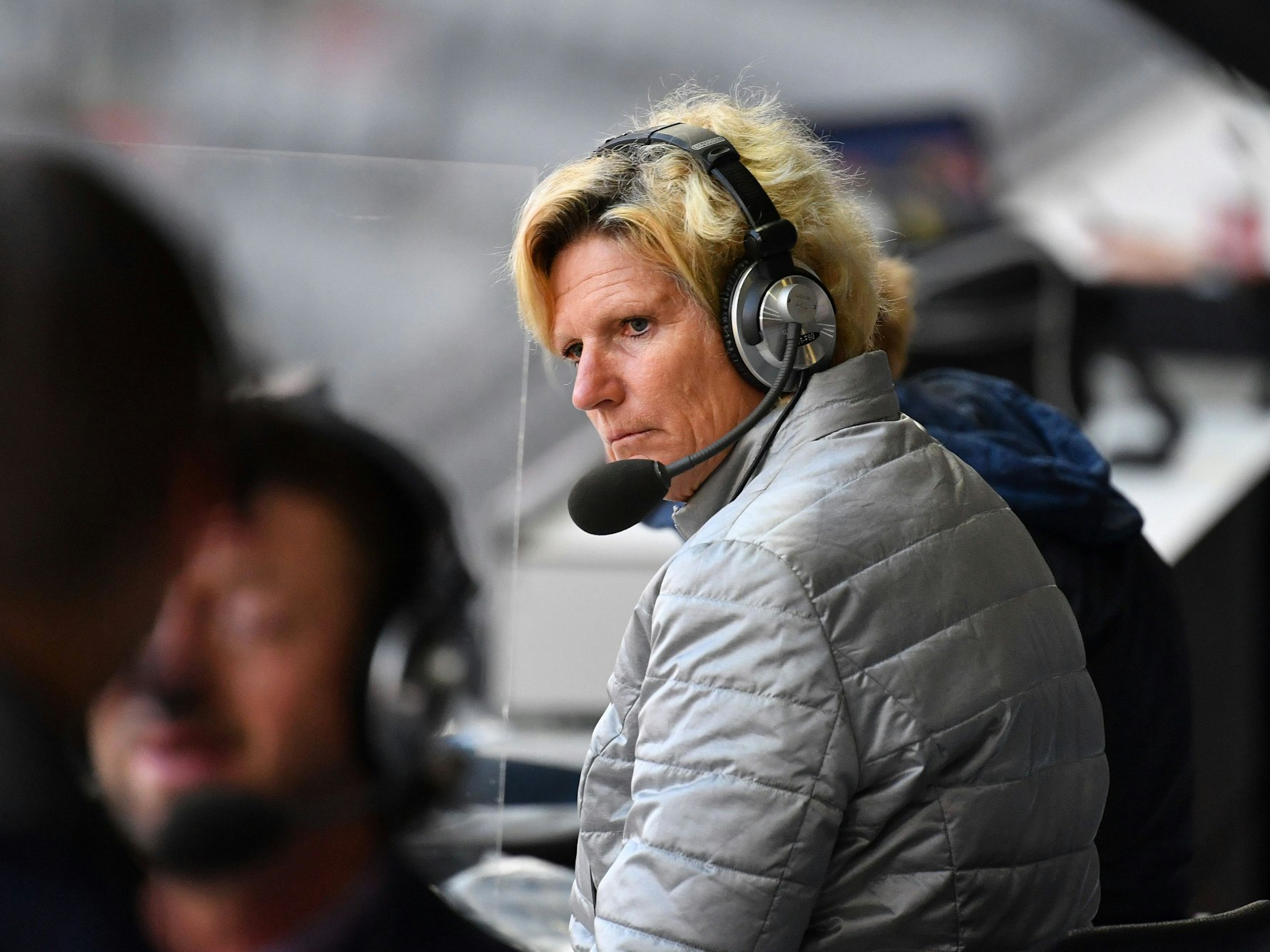 Claudia Neumann mit Headset auf der Tribüne.