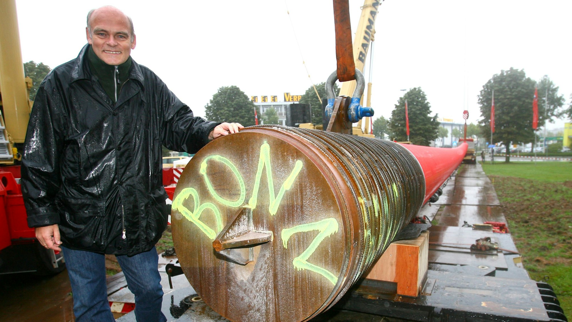 Künstler Lutz Fritsch steht neben seiner roten Stele, die kurz darauf am Verteilerkreis in Köln aufgestellt wurde.