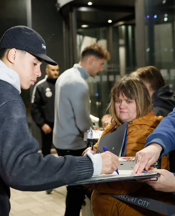 Jamal Musiala (l) und Leon Goretzka geben wartenden Fans bei der Anreise des Kaders ins Frankfurter Teamhotel, dem Hotel Melia Frankfurt City, Autogramme.