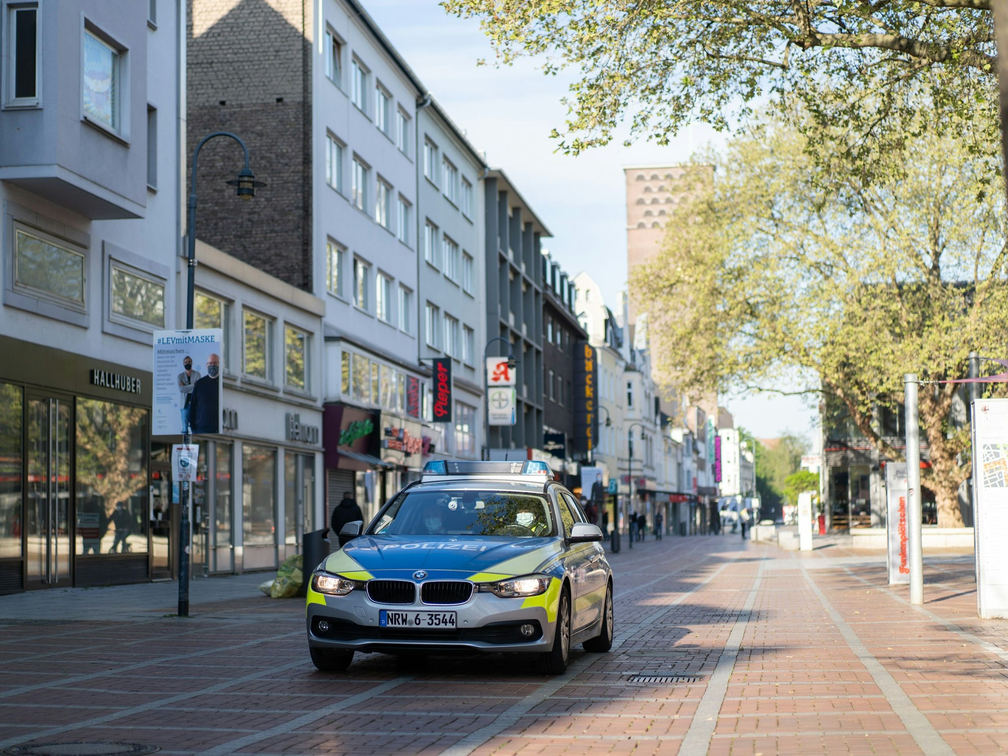Ein Polizeiauto fährt durch die Fußgängerzone in Leverkusen.
