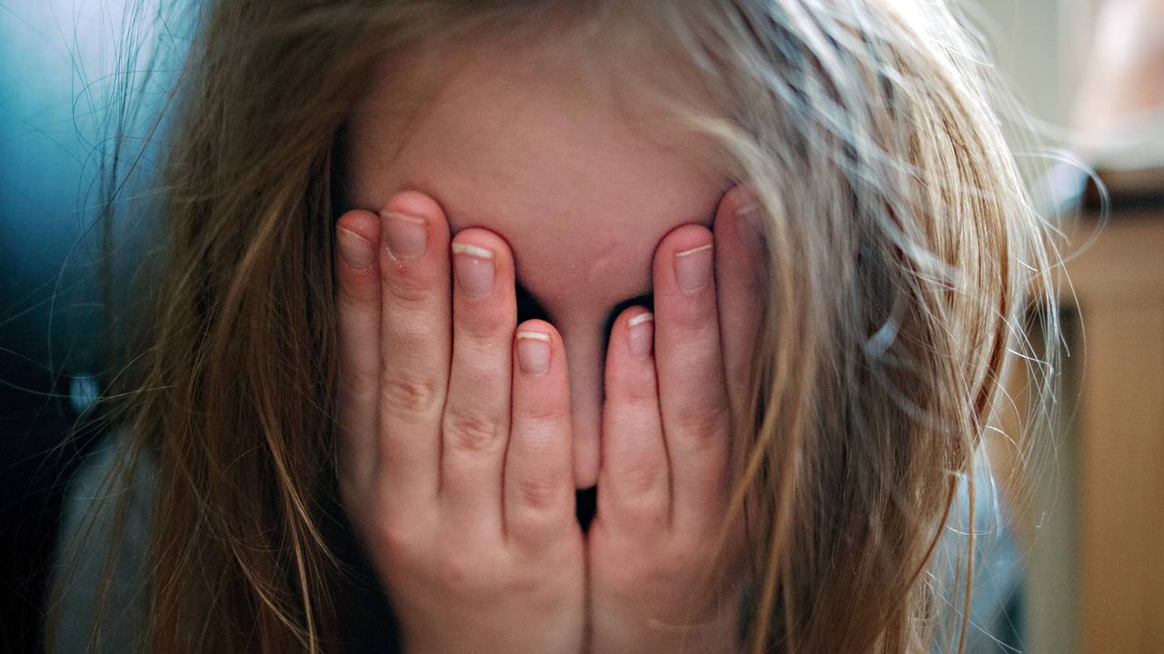 Ein junges Mädchen hält sich die Hände vor ihr Gesicht.