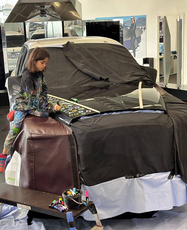 Mikail Akar sitzt auf der Motorhaube eines Rolls-Royce.