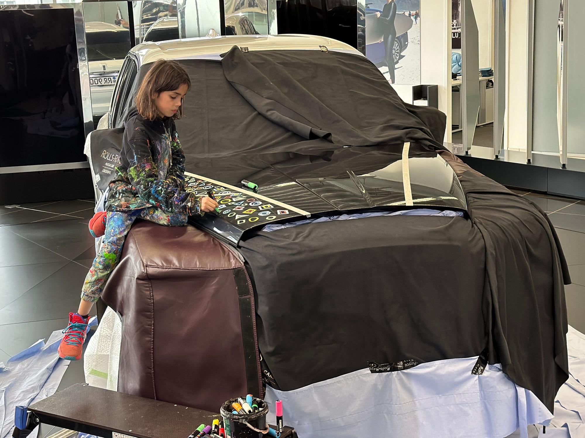 Mikail Akar sitzt auf der Motorhaube eines Rolls-Royce.