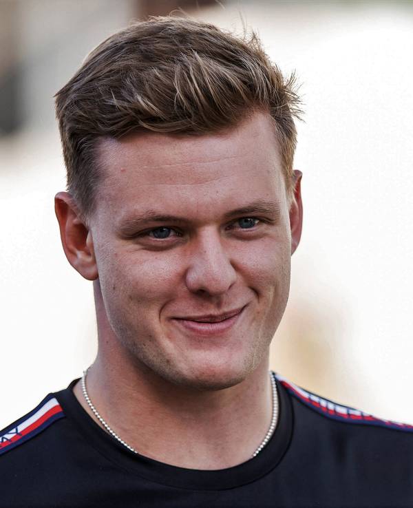 Mick Schumacher grinst beim Gang durch das Fahrerlager der Formel 1.