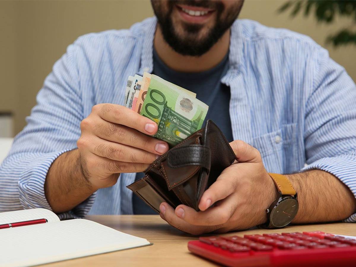 Mann zieht Euro Geldscheine aus der Geldbörse.