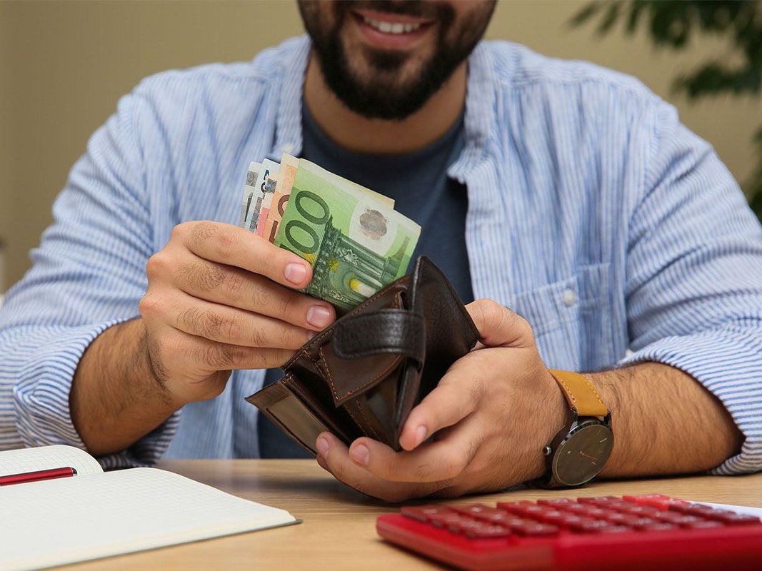 Mann zieht Euro Geldscheine aus der Geldbörse.