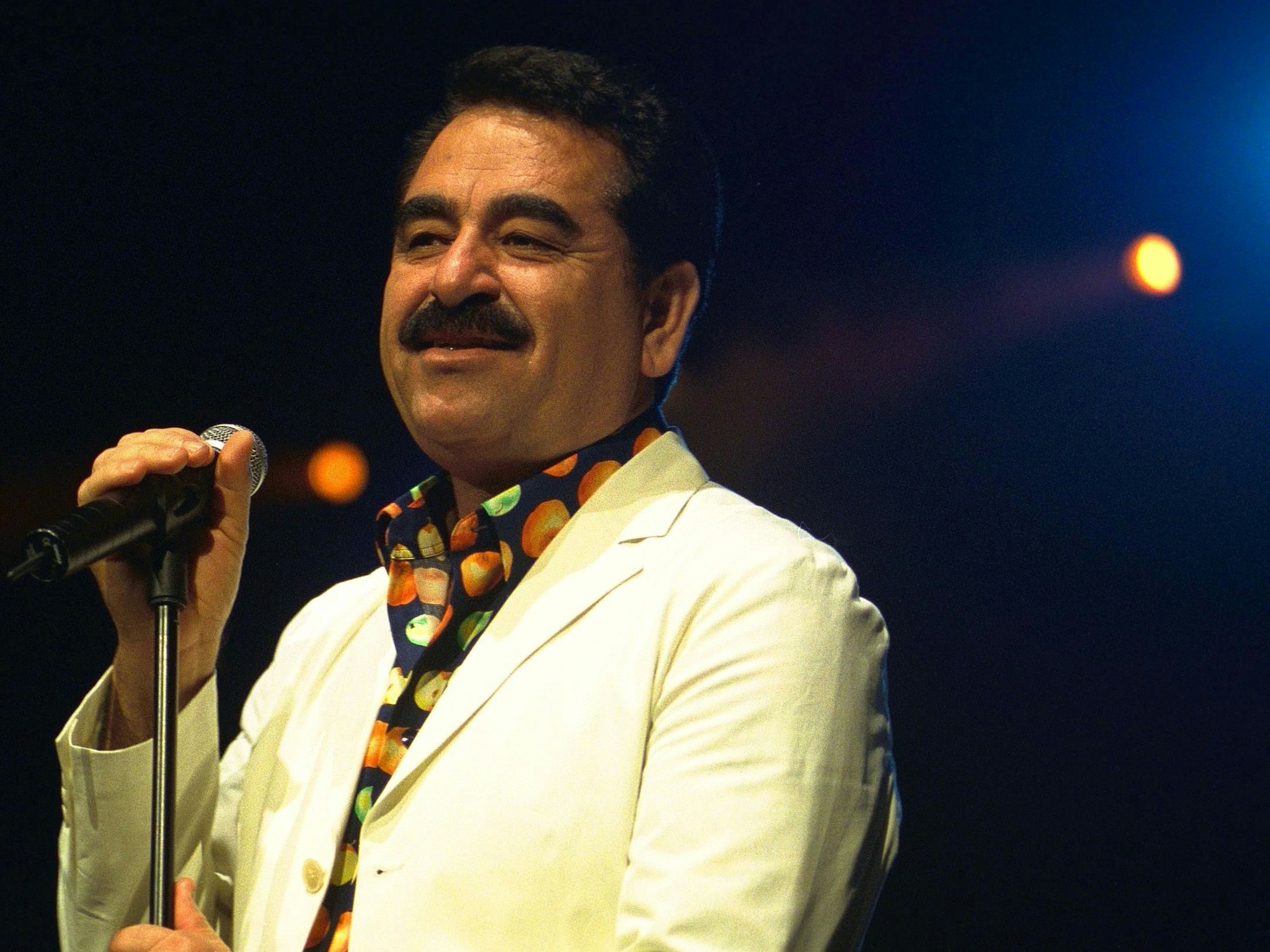 Ibrahim Tatlises steht vor einem Mikrofon auf einer Bühne.