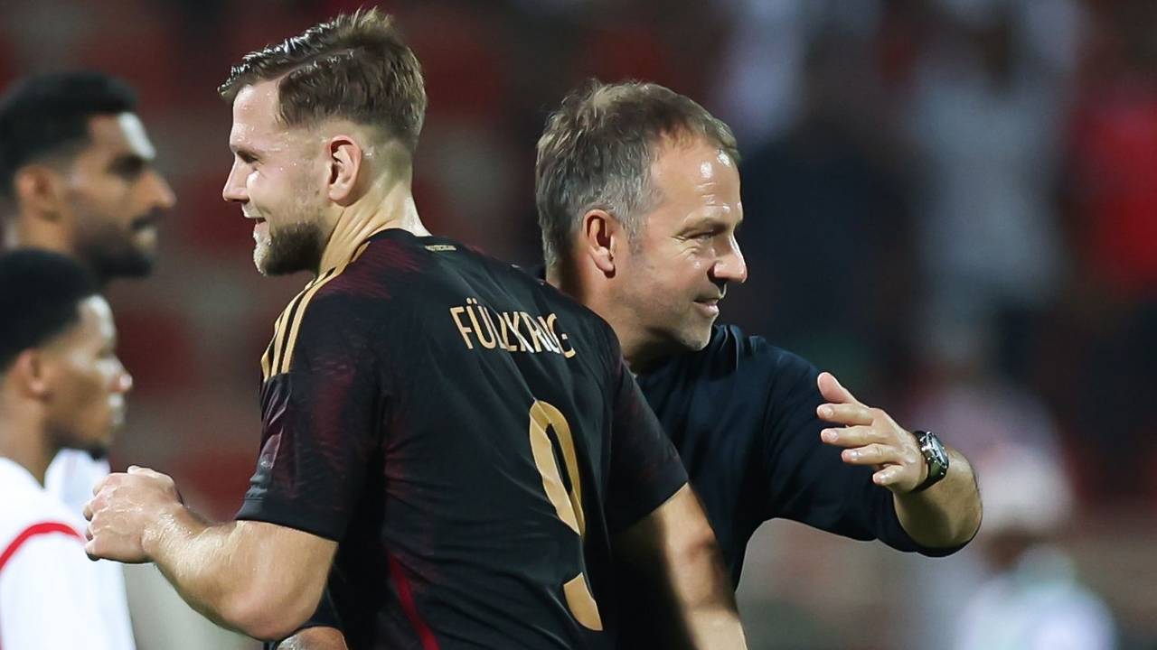 Niclas Füllkrug geht zufrieden am Bundestrainer Hansi Flick vorbei. Flick klopft Füllkrug auf den Rücken.