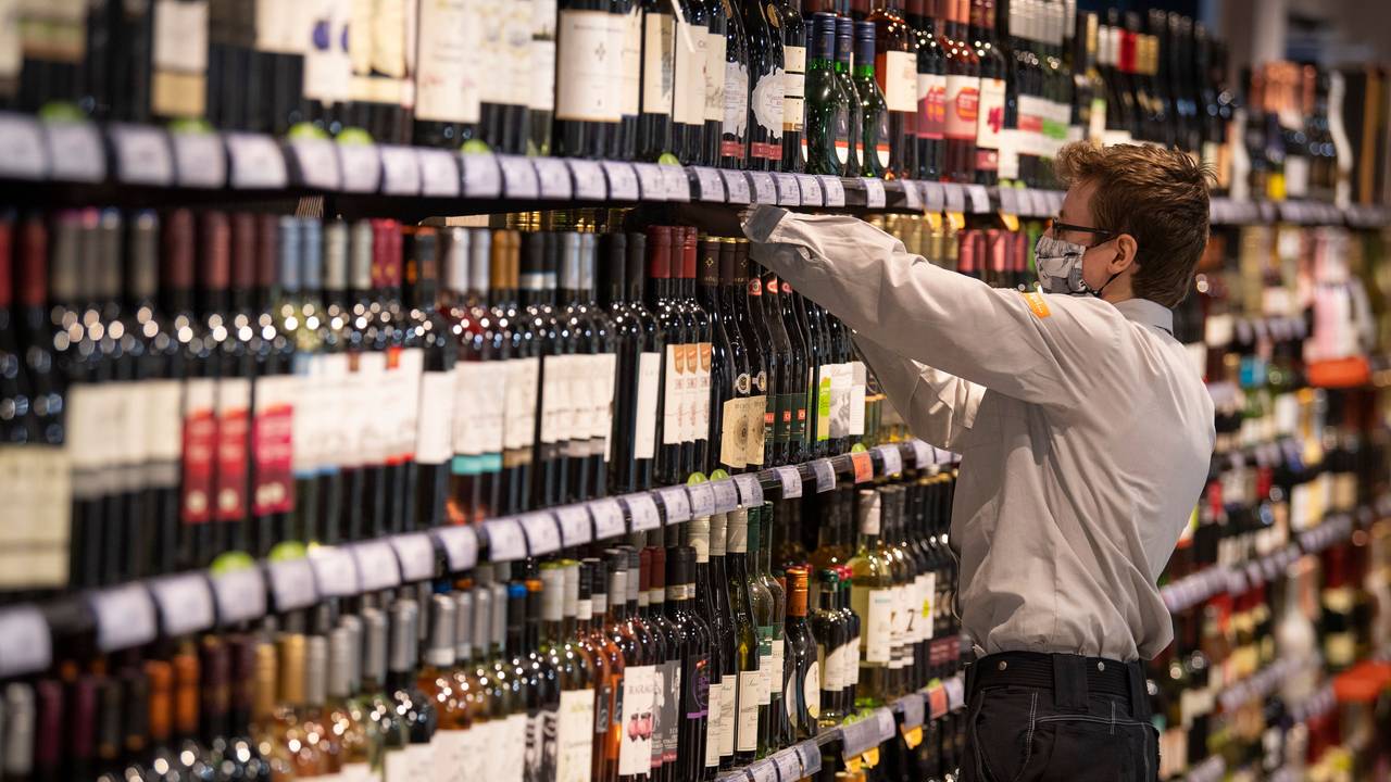Ein Mitarbeiter in einem Supermarkt, hier im Juli 2020, sortiert in einer Filiale in Frankfurt am Main Alkohol in einem Regal.