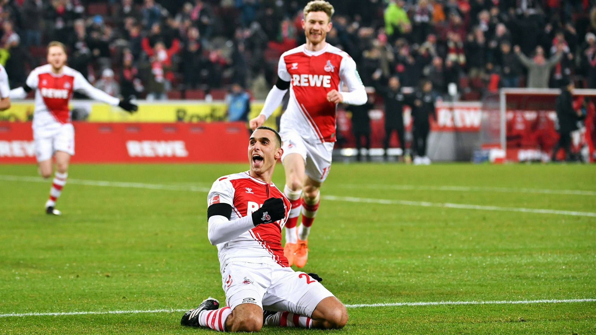 Ellyes Skhiri bejubelt auf Knien rutschend ein Tor für den 1. FC Köln, hinter ihm kommt Florian Kainz dazu.