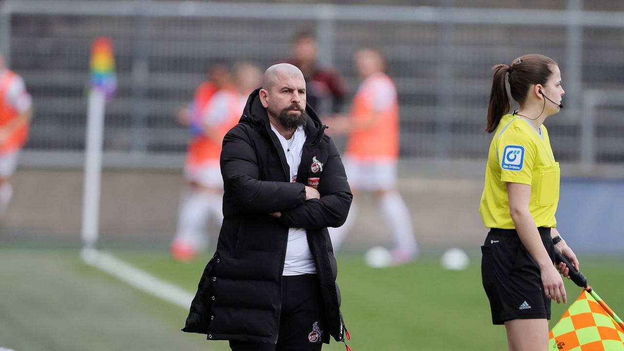 Sascha Glass steht beim Spiel der Frauen des 1. FC Köln gegen den FC Bayern München mit verschränkten Armen an der Seitenlinie.